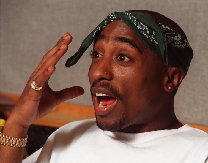 Tupac Shakur wearing a bandana and jewelry