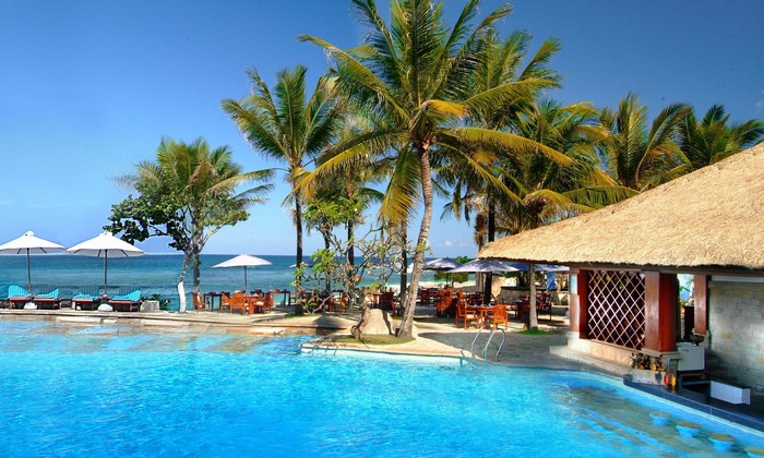 Resort pool and beach with palm trees and ocean view
