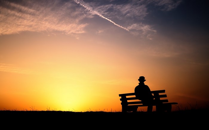 Silhouette of a person on a bench at sunset
