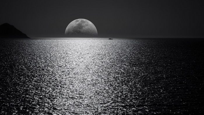 Moon over the ocean with a boat
