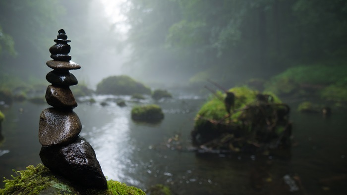 Stacked wet stones in a misty forest stream