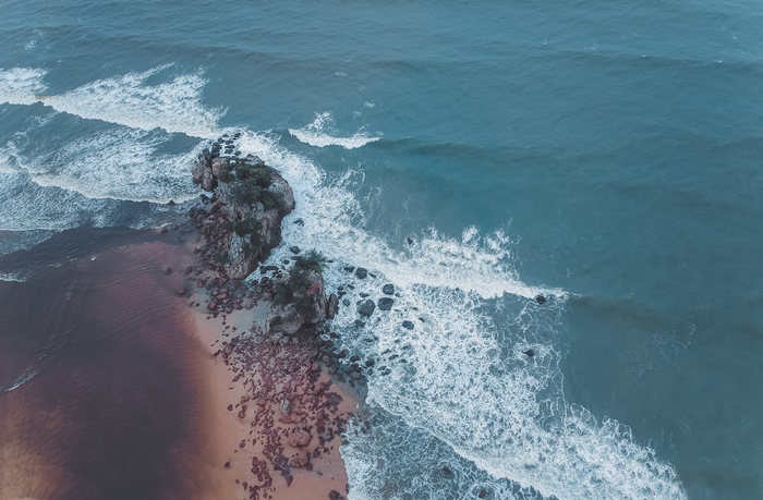 Aerial view of rocky shore with waves crashing