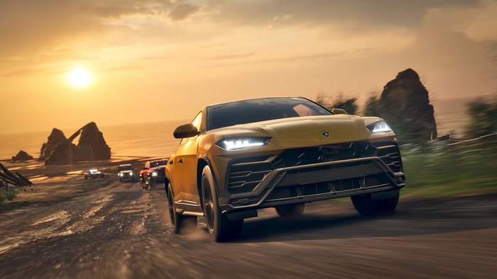 Lamborghini Urus driving on a coastal road at sunset