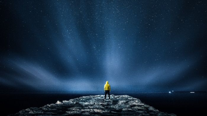 Person in yellow jacket under starry sky