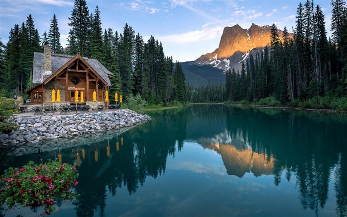 Wooden cabin by a lake with a mountain reflection