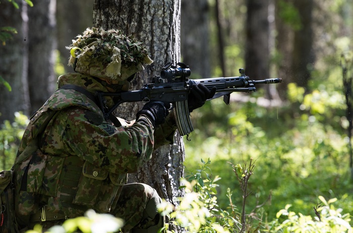Soldier aiming an assault rifle in a forest