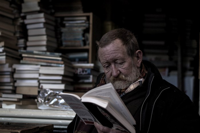 Elderly man reading a book in a bookstore