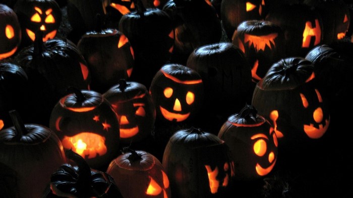 A collection of carved Halloween pumpkins glowing in the dark