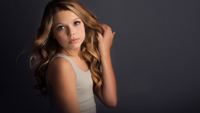 Girl with blonde wavy hair against a dark background