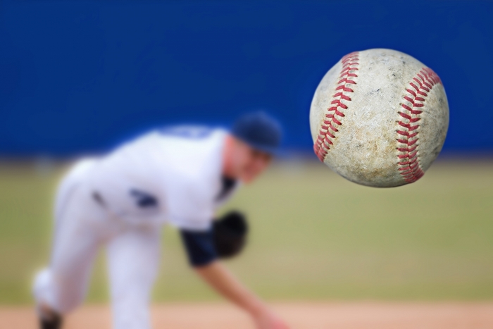 Baseball in motion with pitcher