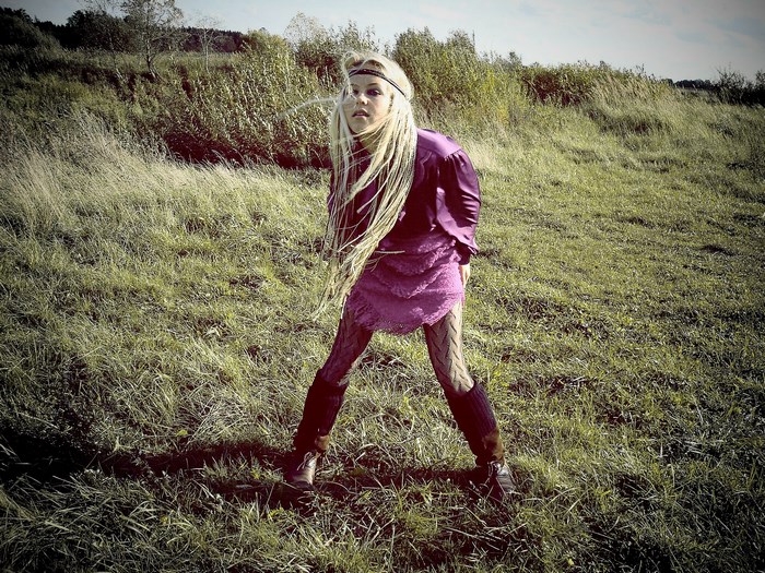 Woman with blonde dreadlocks in a field