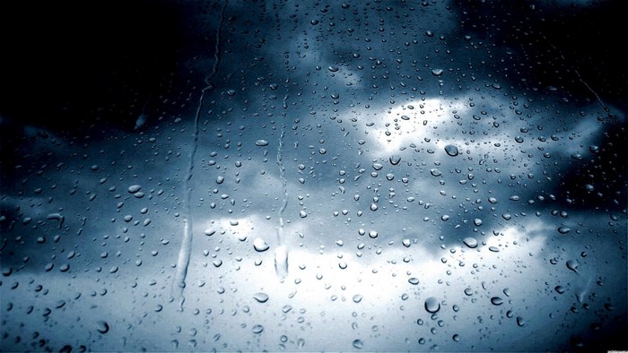 Raindrops on a window with stormy clouds