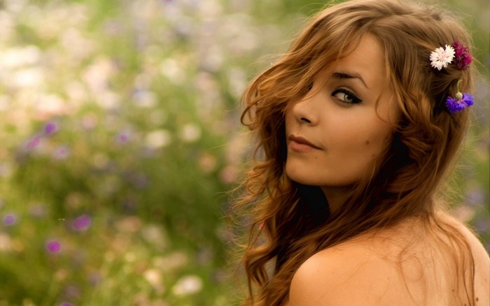 Young woman with flowers in her hair in a field
