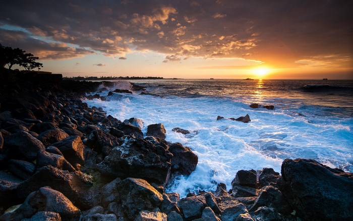 Sunset over rocky Hawaiian coast with ocean waves