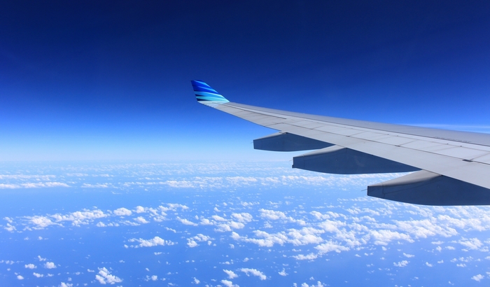 Airplane wing flying over clouds