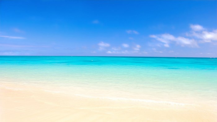 Turquoise ocean and sandy beach under blue sky