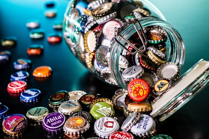 Jar of beer bottle caps spilled on a table