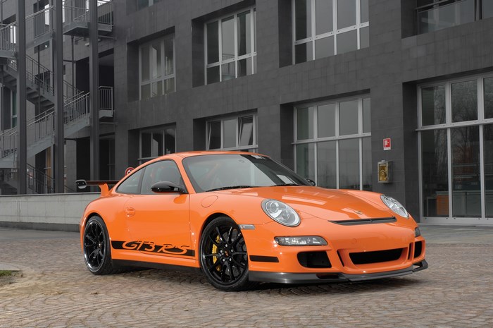 Orange Porsche GT3 RS parked in front of a modern building