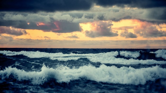 Ocean waves at sunset with dramatic clouds