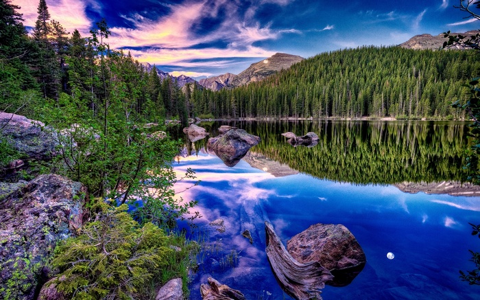 Lake reflection of pine forest and mountains at sunset
