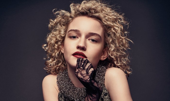 Julia Garner with curly blonde hair and red lipstick