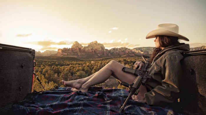Woman with Rifle Relaxing in Scenic Desert Landscape
