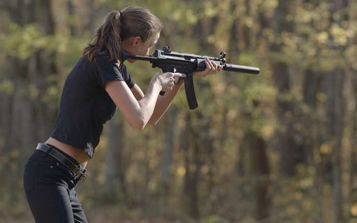 Woman aiming a rifle in a forest