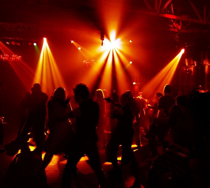People dancing in a club with red and yellow lights