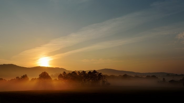Sunrise over misty hills and trees