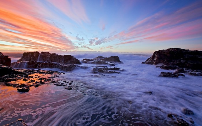 Ocean waves crashing on rocks at sunset