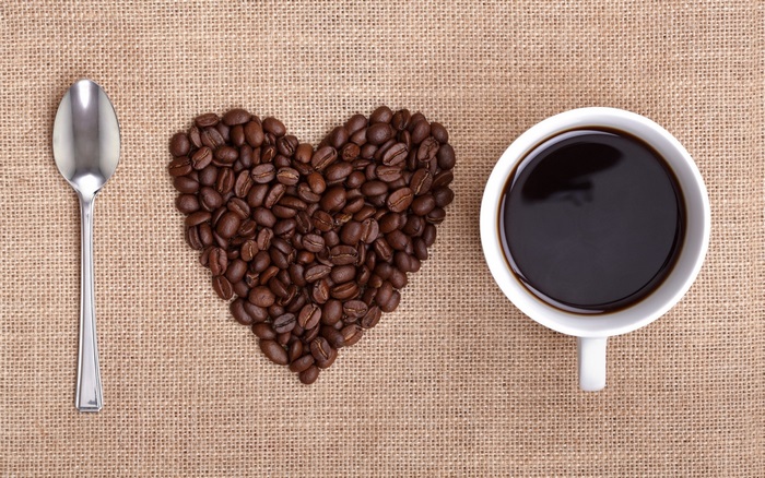 Coffee cup, spoon, and heart shape of coffee beans