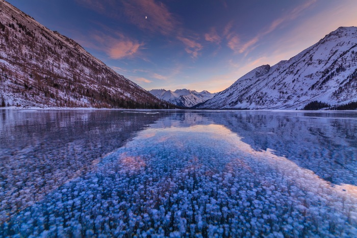 Frozen Lake Between Snowy Mountains at Sunset