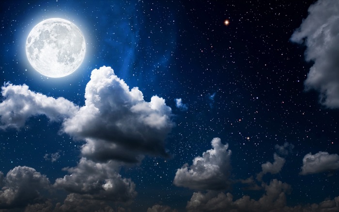 Full moon in a starry night sky with clouds