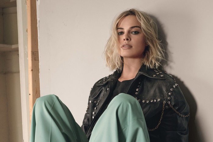Margot Robbie in leather jacket and green pants