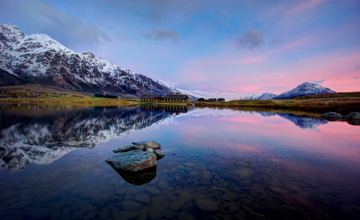 Lake reflection of snow-capped mountains at sunset