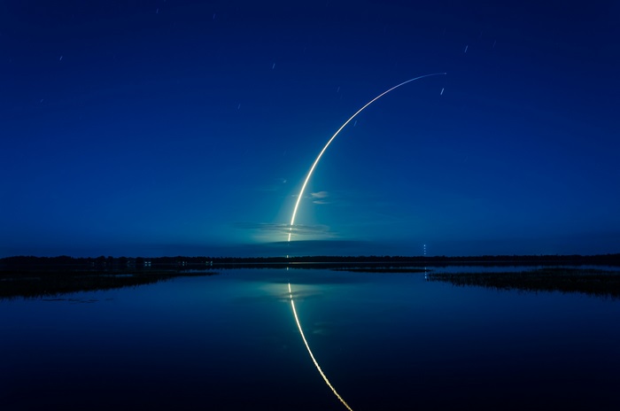 Falcon 9 rocket launch over water at night