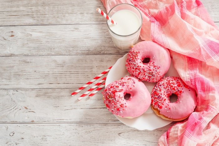 Pink frosted donuts with sprinkles and milk
