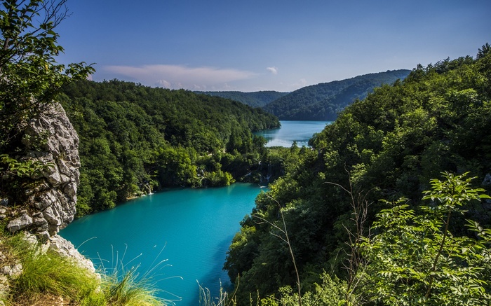 Turquoise lake surrounded by green forest and rocky cliffs
