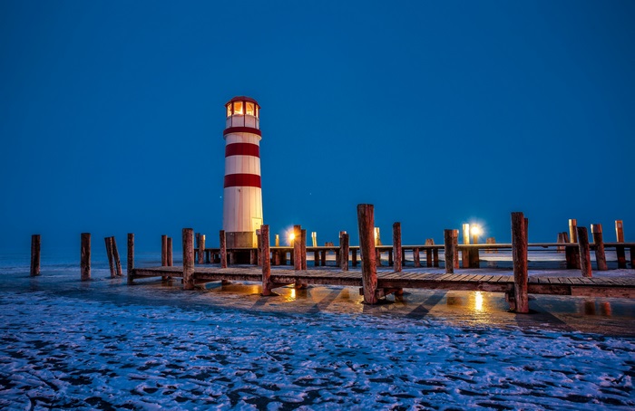 Lighthouse on a frozen lake at dusk