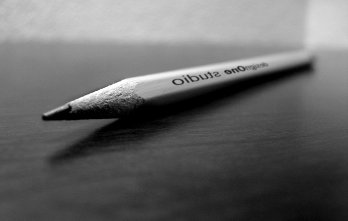Pencil with text 'design one studio' on a dark surface