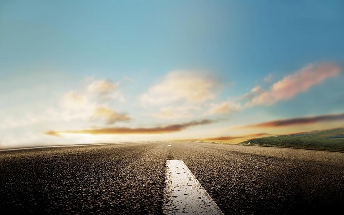 Road stretching to the horizon under a sunset sky