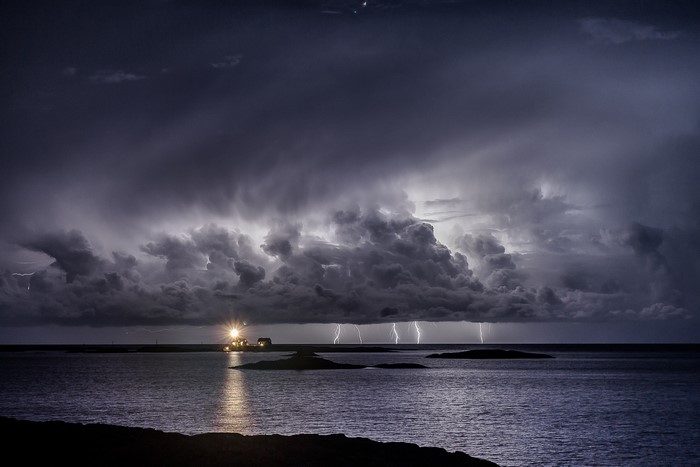 Lightning storm over the sea with a lighthouse