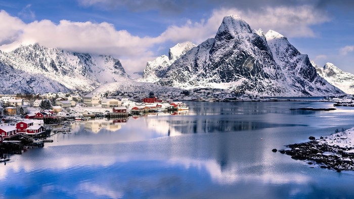 Snowy mountains overlooking a village by the water