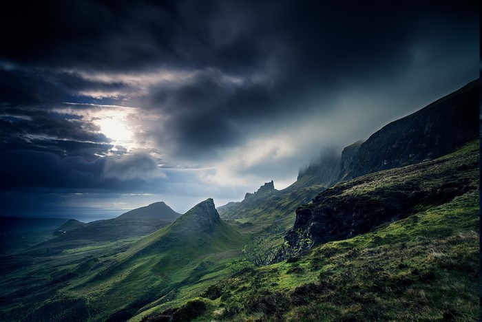 Dramatic clouds over green hills and sea in Scotland