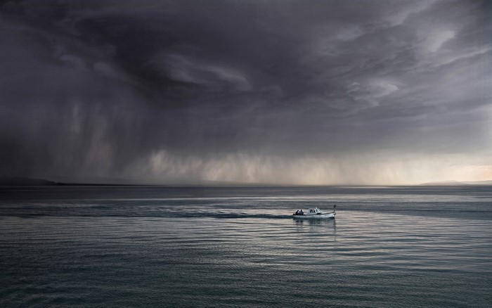 Boat sailing through a stormy sea under dark clouds