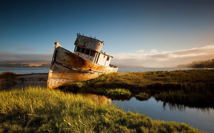Shipwreck on the shore with calm water and hills