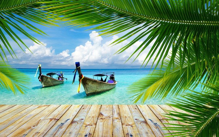 Tropical beach with longtail boats and palm trees