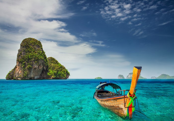 Longtail boat in turquoise water near limestone islands