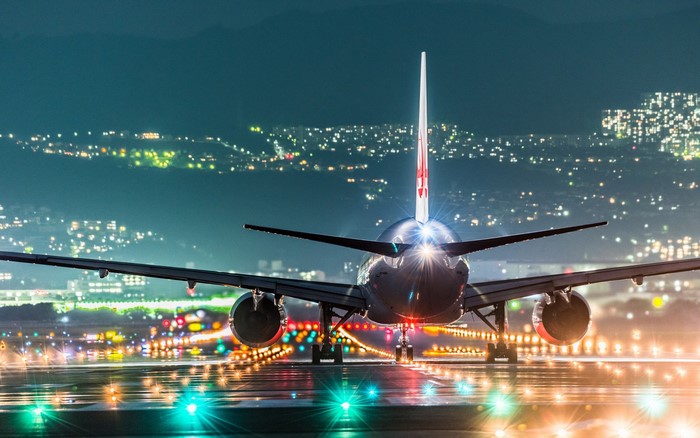 Airplane on runway at night with city lights