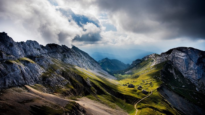 Mountain range with dramatic clouds and a winding path